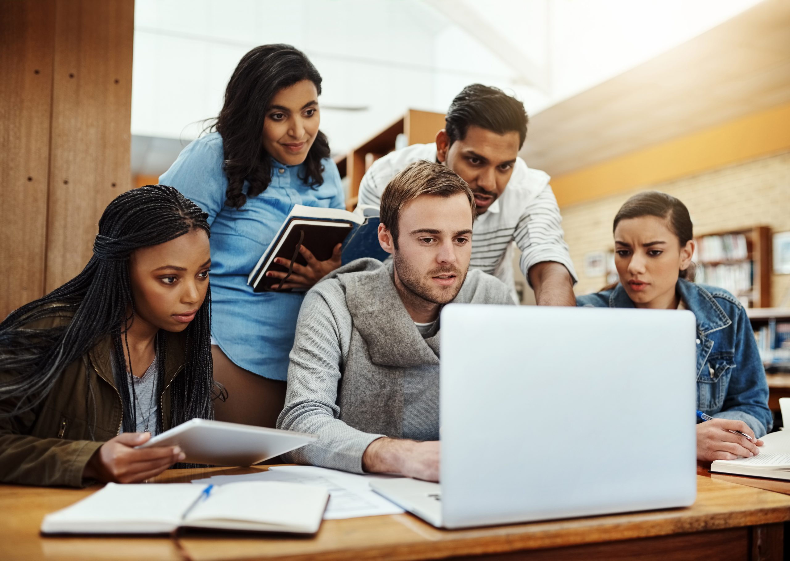 Students gather around a laptop for discussion.